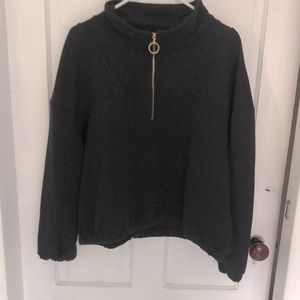 Black horizontal ribbed top with standout  gold ring zipper on neckline.